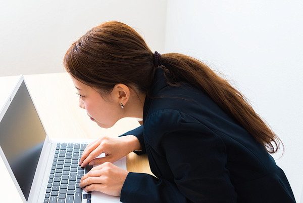 猫背でパソコンの画面を見る女性