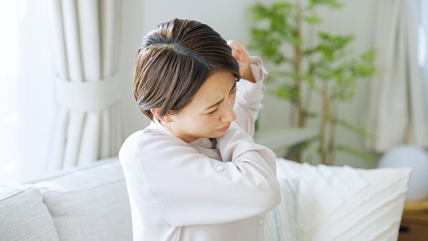 四十肩・五十肩の痛みで肩を押さえる女性